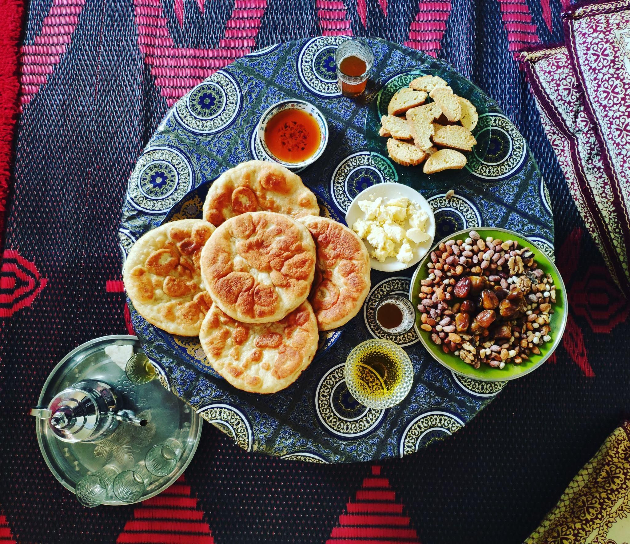 Una mesa con pan plano, frutos secos, queso y un hervidor de agua.