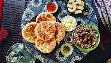 Una mesa con pan plano, frutos secos, queso y un hervidor de agua.