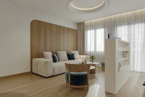 A modern living room with a sofa, a round table, and a bookshelf. - Elyra Hotel Phu Quoc  (Phu Quoc)
