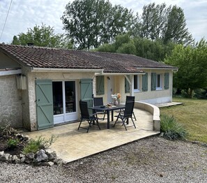 A house with a patio, a table with chairs, and a small garden area. - Holiday Home 'Tournesol' with Private Pool, Wi-Fi and Air Conditioning (Tournon-d'Agenais)