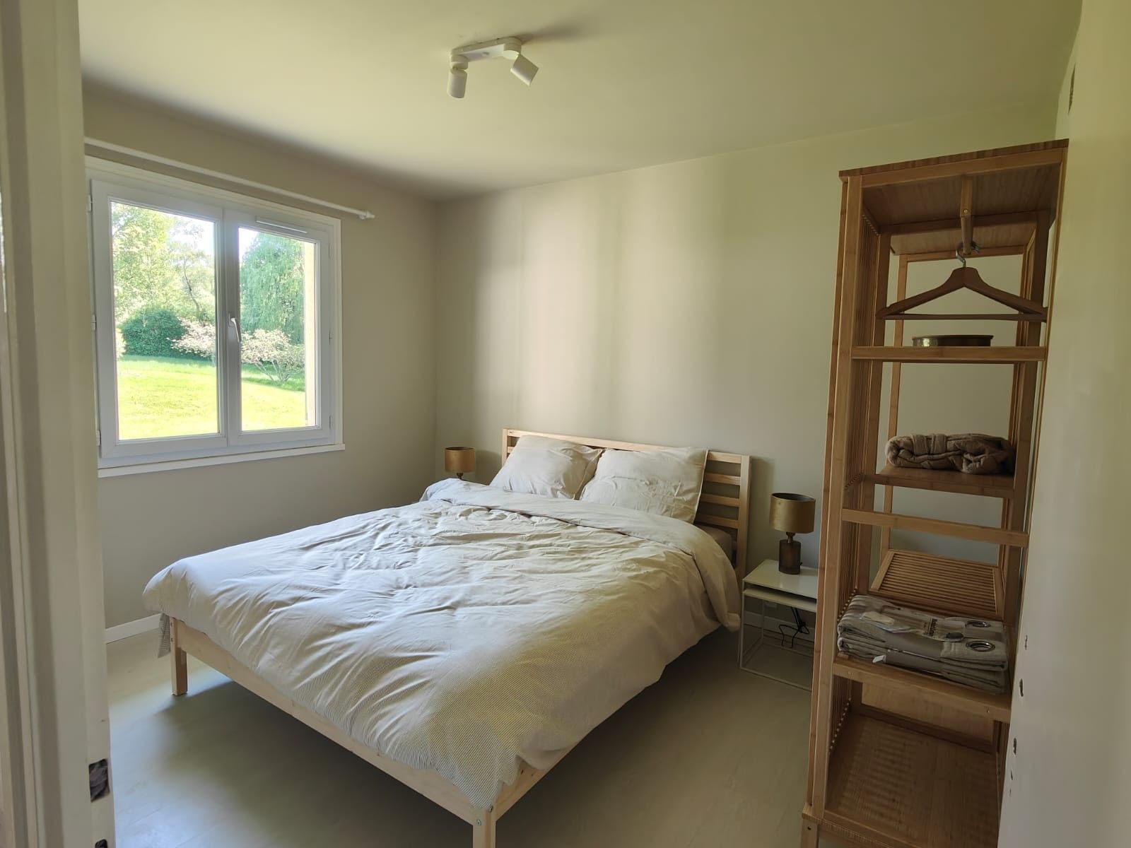 A bedroom with a bed, bedside table, lamp, and a wooden wardrobe.