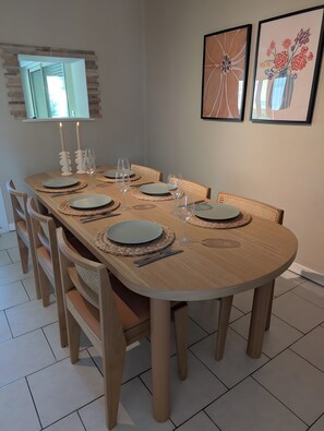 Comedor con una mesa de madera dispuesta para seis personas, rodeada de seis sillas.