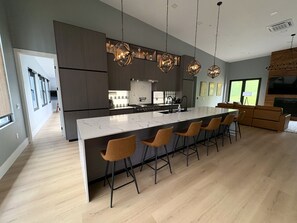 A modern kitchen with a large island, bar stools, and pendant lighting. - New Spacious Mountain Modern Home • 5 bedroom/5 Bath • Walk Wisp • Sauna/Hot Tub (McHenry)