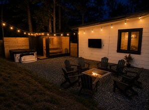 Eine Außenpatio-Terrasse mit Feuerstelle, Sitzgelegenheiten und Lichterketten.