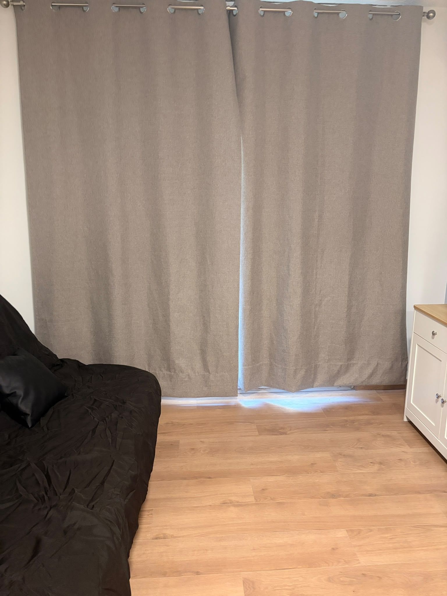 Ein Zimmer mit einem Bett, einem Nachttisch und einem Vorhang.