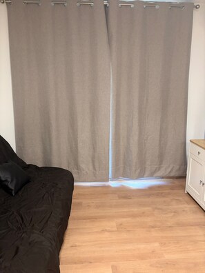 Ein Zimmer mit einem Bett, einem Nachttisch und einem Vorhang.