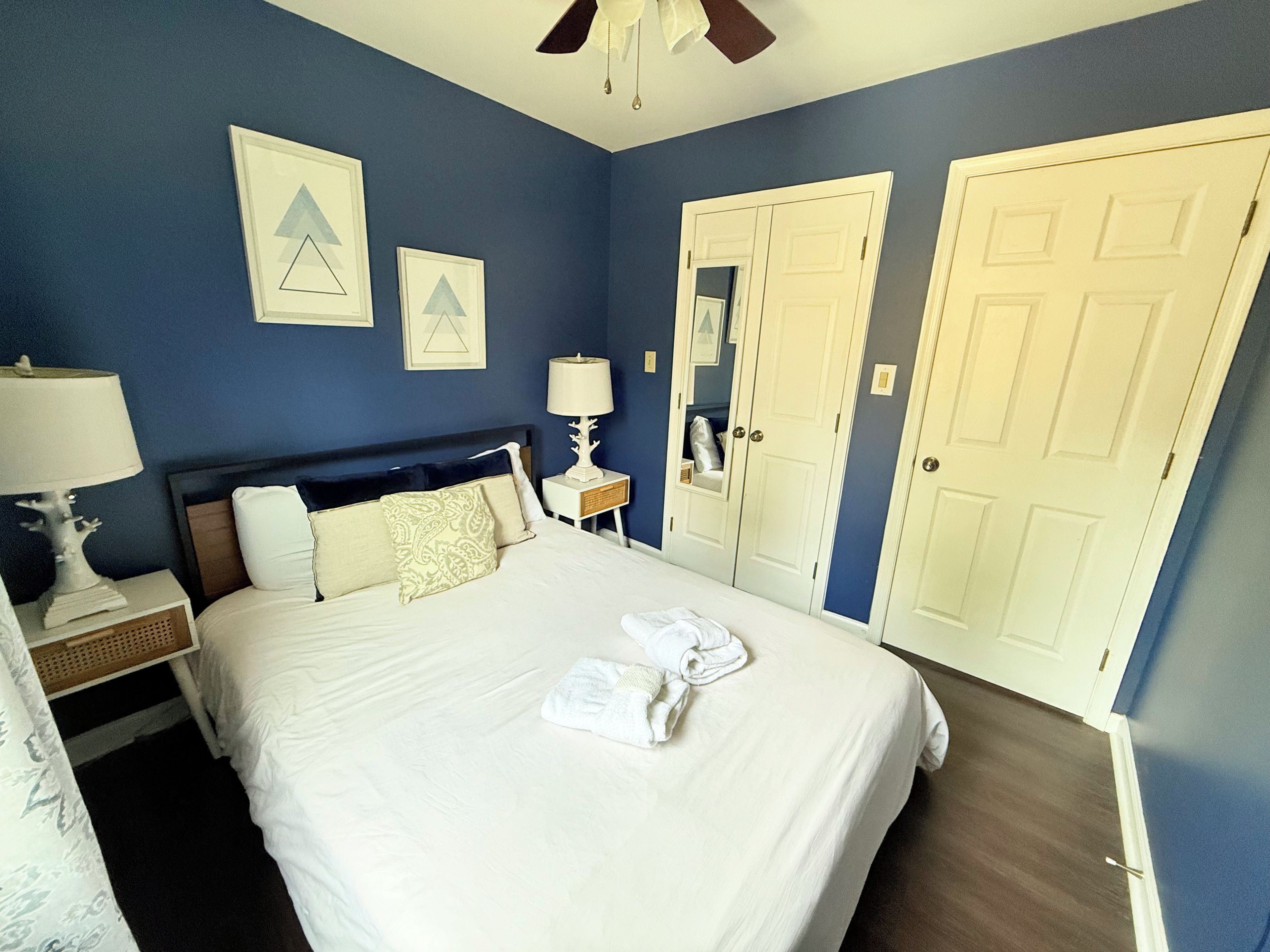 A hotel room with a bed, nightstands, a lamp, a ceiling fan, and a wardrobe.
