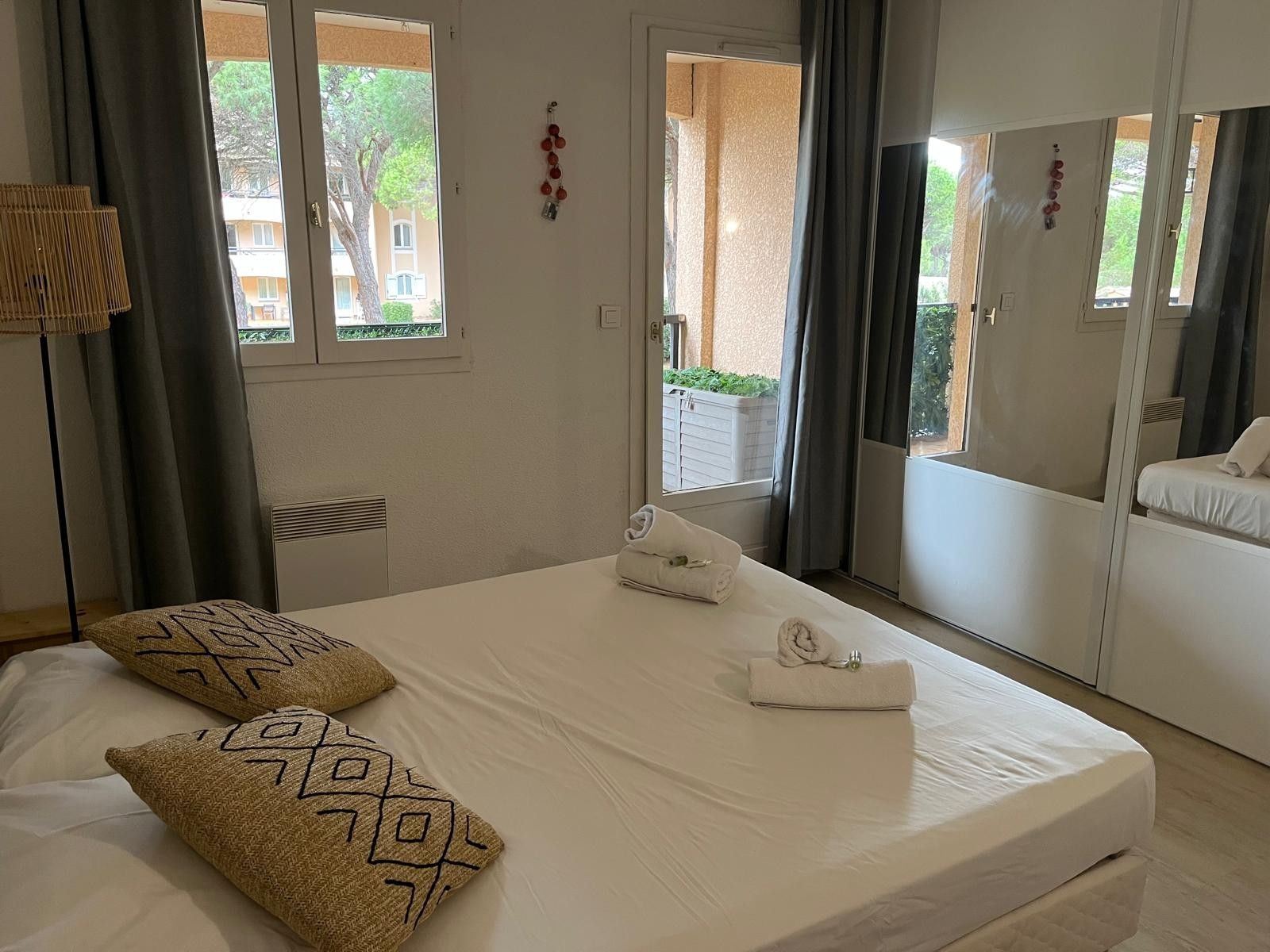 Ein Hotelzimmer mit Bett, Fenster, Tür und Blick ins Freie.