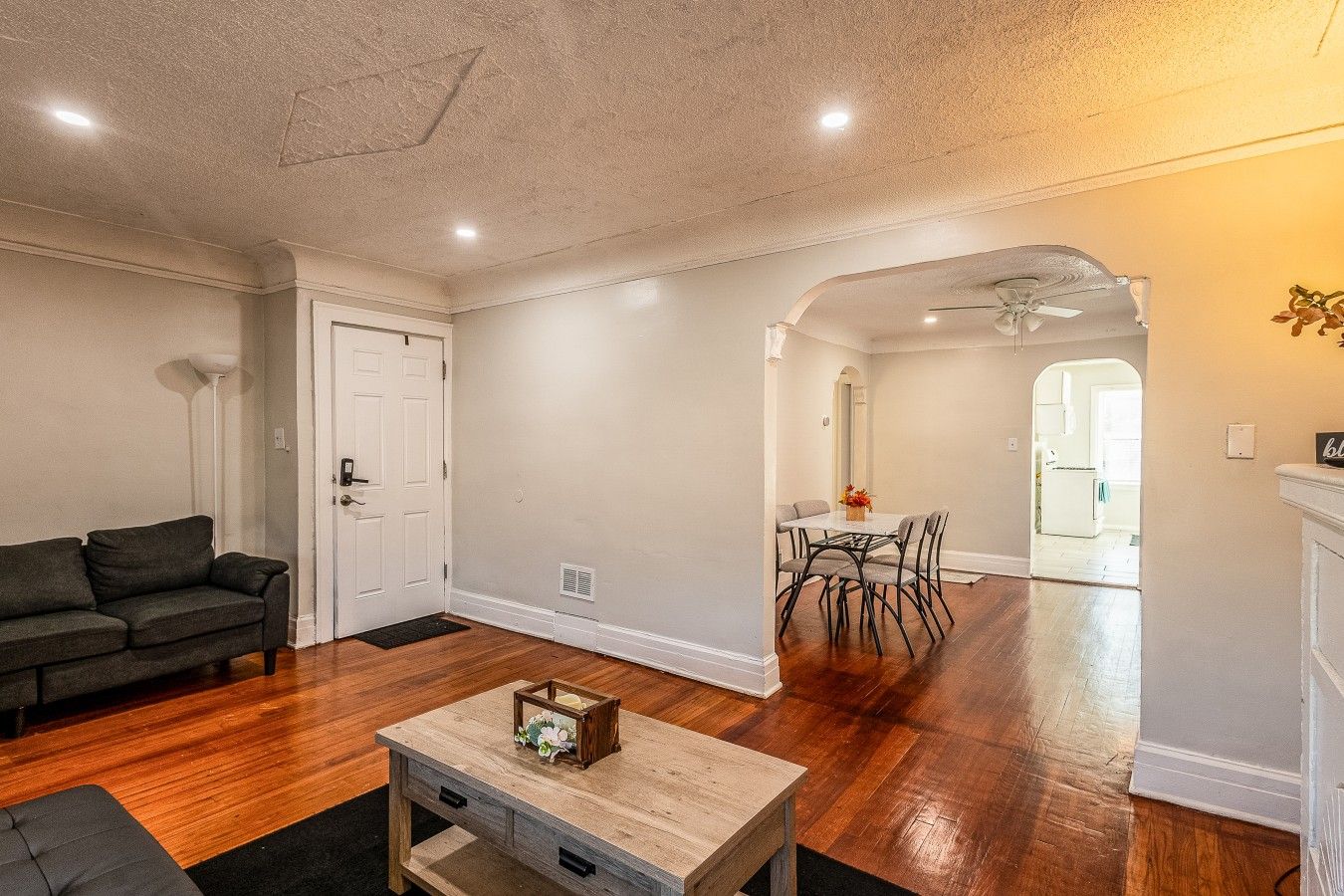 A living room with a sofa, a coffee table, and a dining area with a table and chairs.