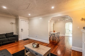 Uma sala de estar com sofá, mesa de centro e área de jantar com mesa e cadeiras.
