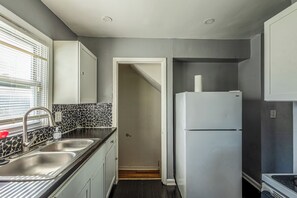 Eine Küche mit einer schwarz-weißen Küchenrückwand, einem Edelstahl-Spülbecken und einem weißen Kühlschrank.