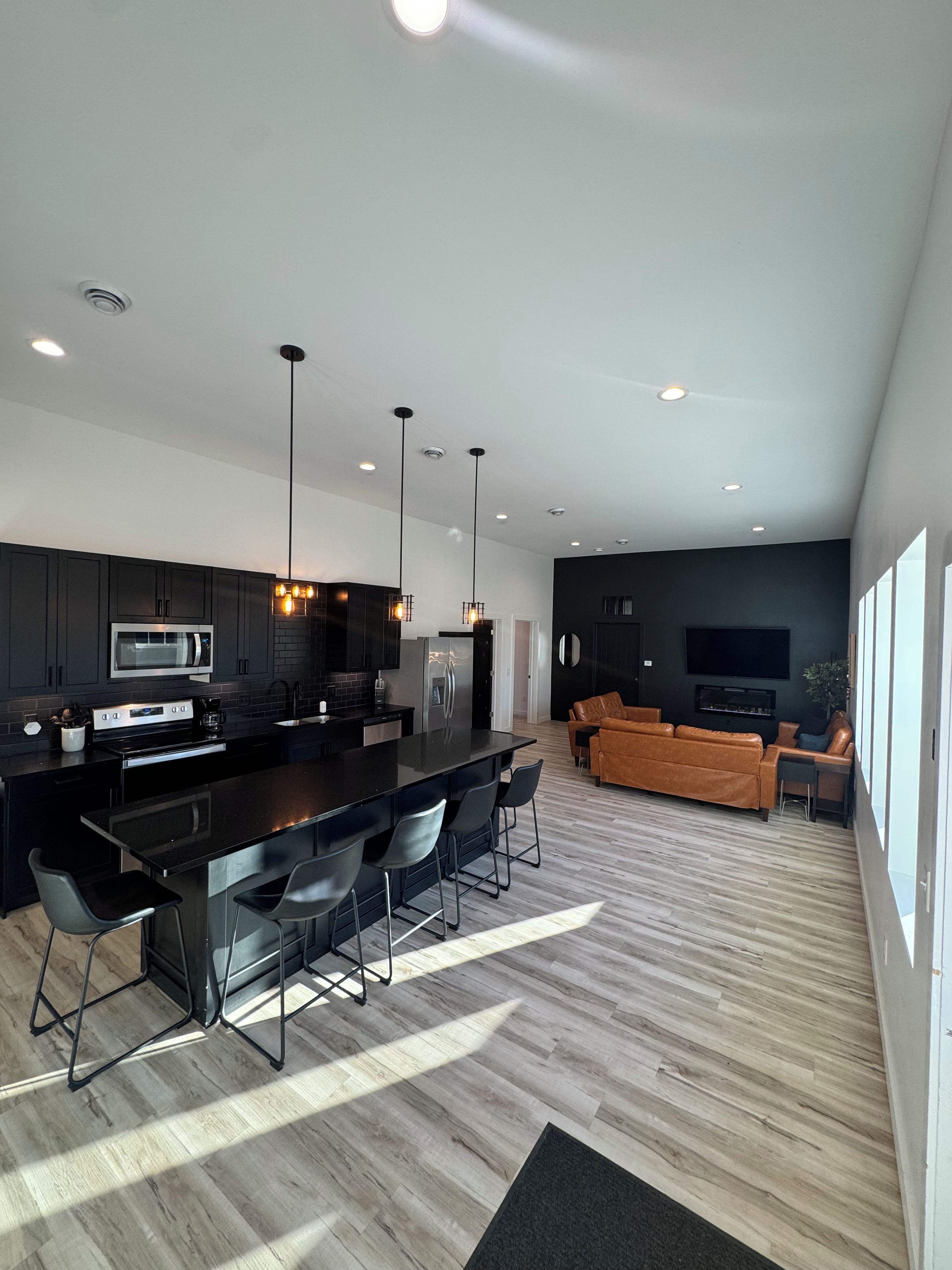 A modern kitchen with a central island, bar stools, and pendant lighting.