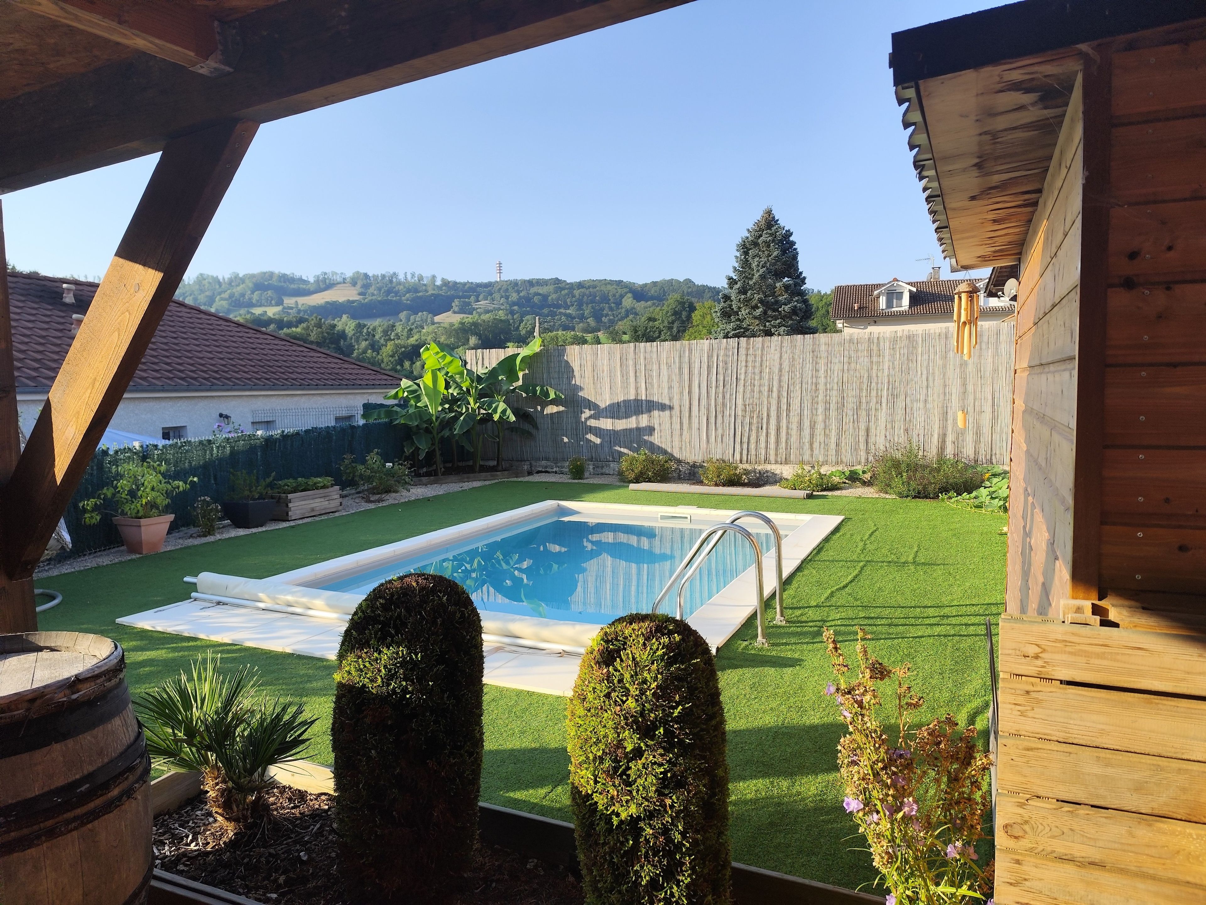 A backyard with a swimming pool, artificial grass, and a wooden deck.