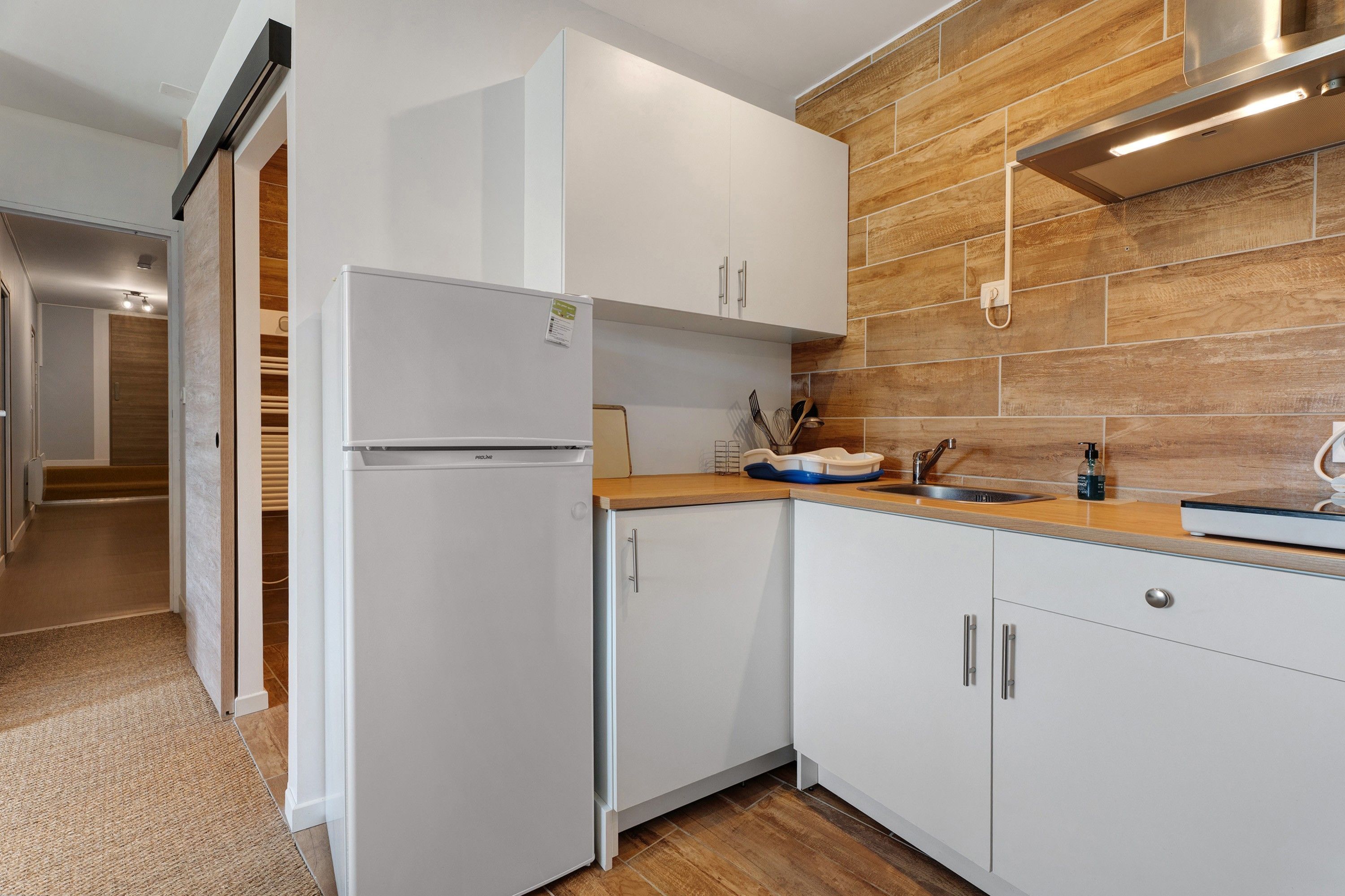 A modern kitchen with white cabinetry, a built-in oven, and a wooden backsplash.
