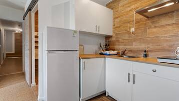 A modern kitchen with white cabinetry, a built-in oven, and a wooden backsplash.