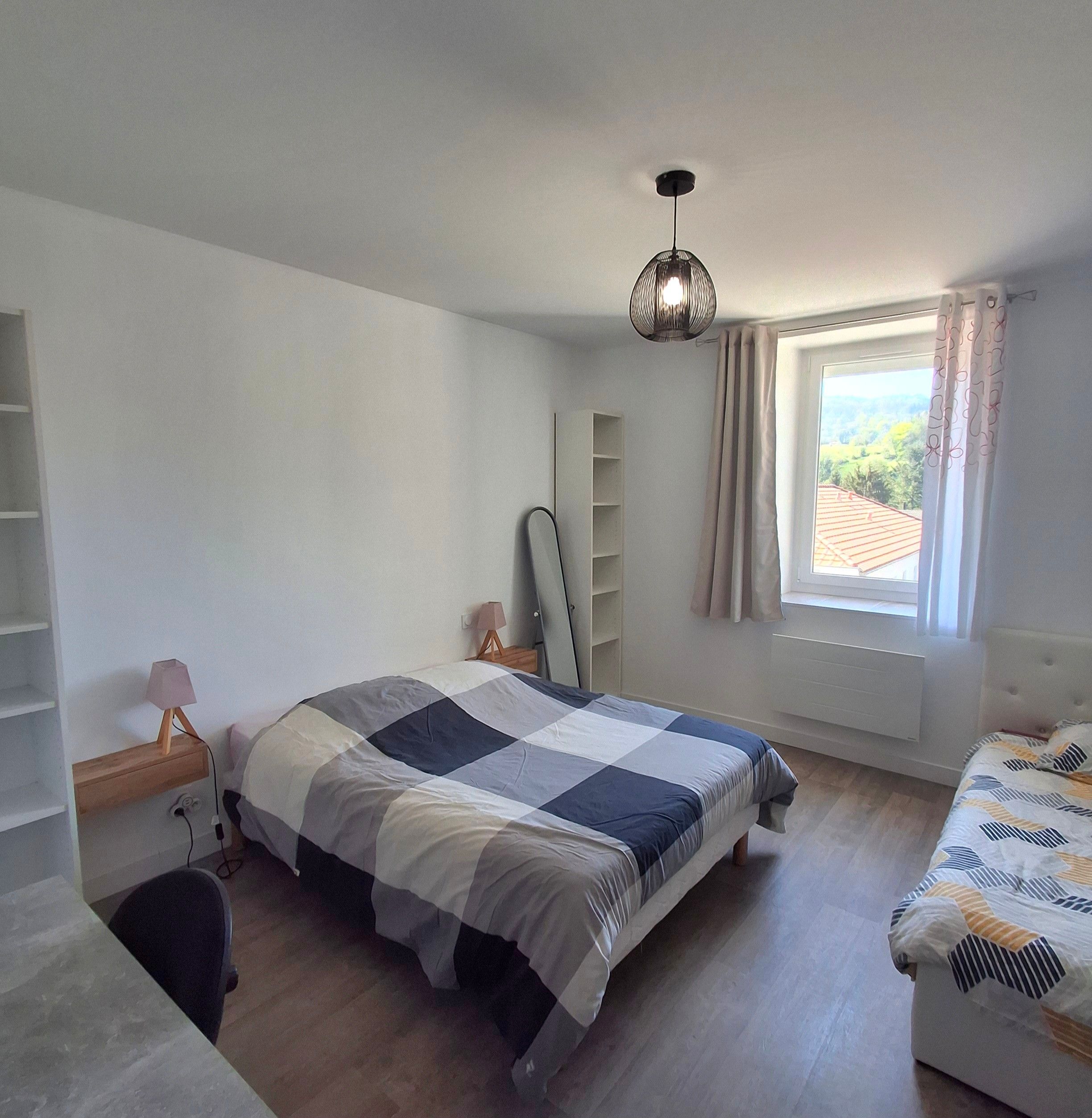 Un dormitorio con cama, escritorio, silla, armario y ventana con cortinas.
