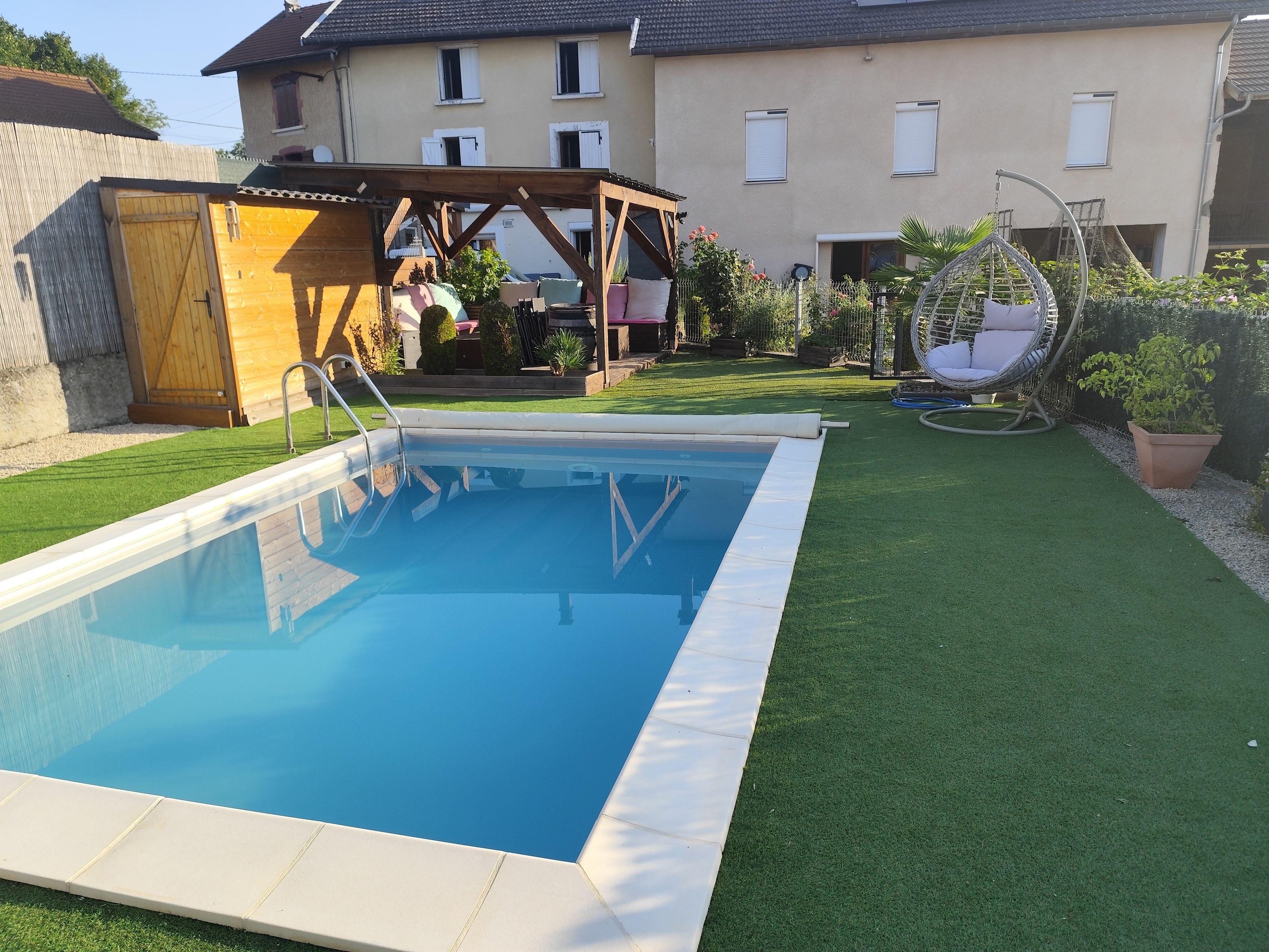 A swimming pool with a wooden deck and a pergola in a backyard.