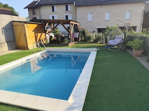 Una piscina con cubierta de madera y pérgola en un patio trasero.