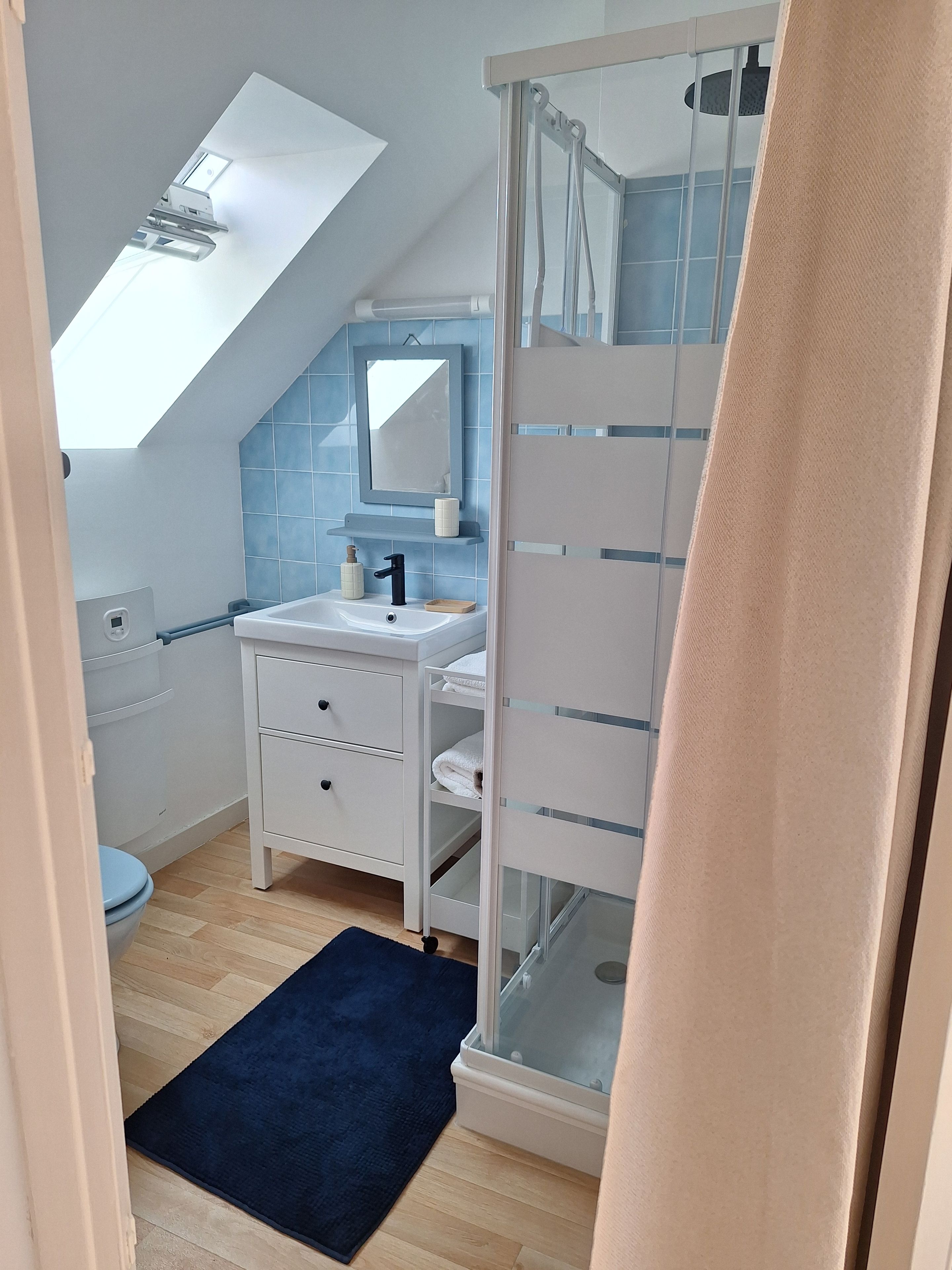 A modern bathroom with a skylight, a white sink, a mirror, and a glass shower enclosure.