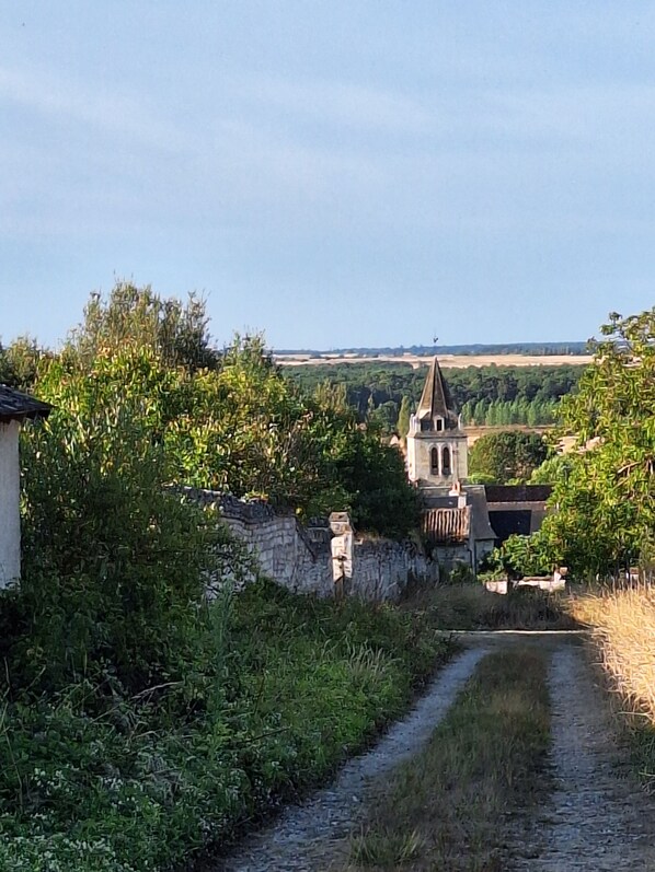 A rural landscape with a church, a stone wall, and a narrow path.