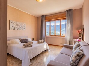 Una habitación de hotel con una cama, un sofá, una ventana con vistas a la montaña y un cuadro en la pared.