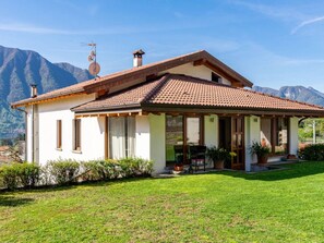 Una casa de una planta con techo de tejas, un porche cubierto y un césped cuidado.