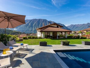 Una villa con piscina, mobiliario exterior y vistas a la montaña.