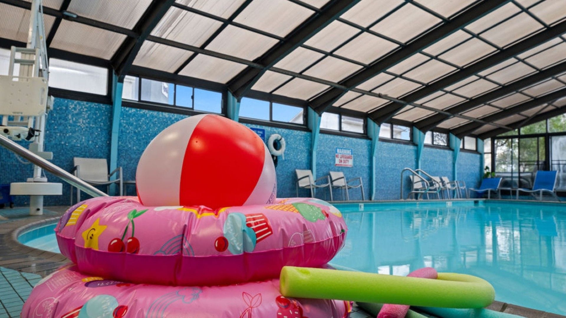 An indoor swimming pool with a beach ball and inflatable toys.