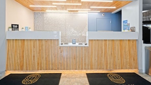 A reception desk with a modern design, featuring a wooden panel wall and a digital display screen. - Barclay Towers by CoolVacay (Virginia Beach)