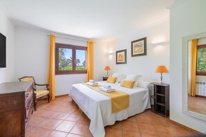 Una habitació d'hotel amb llit, làmpades laterals, escriptori i cadira.
