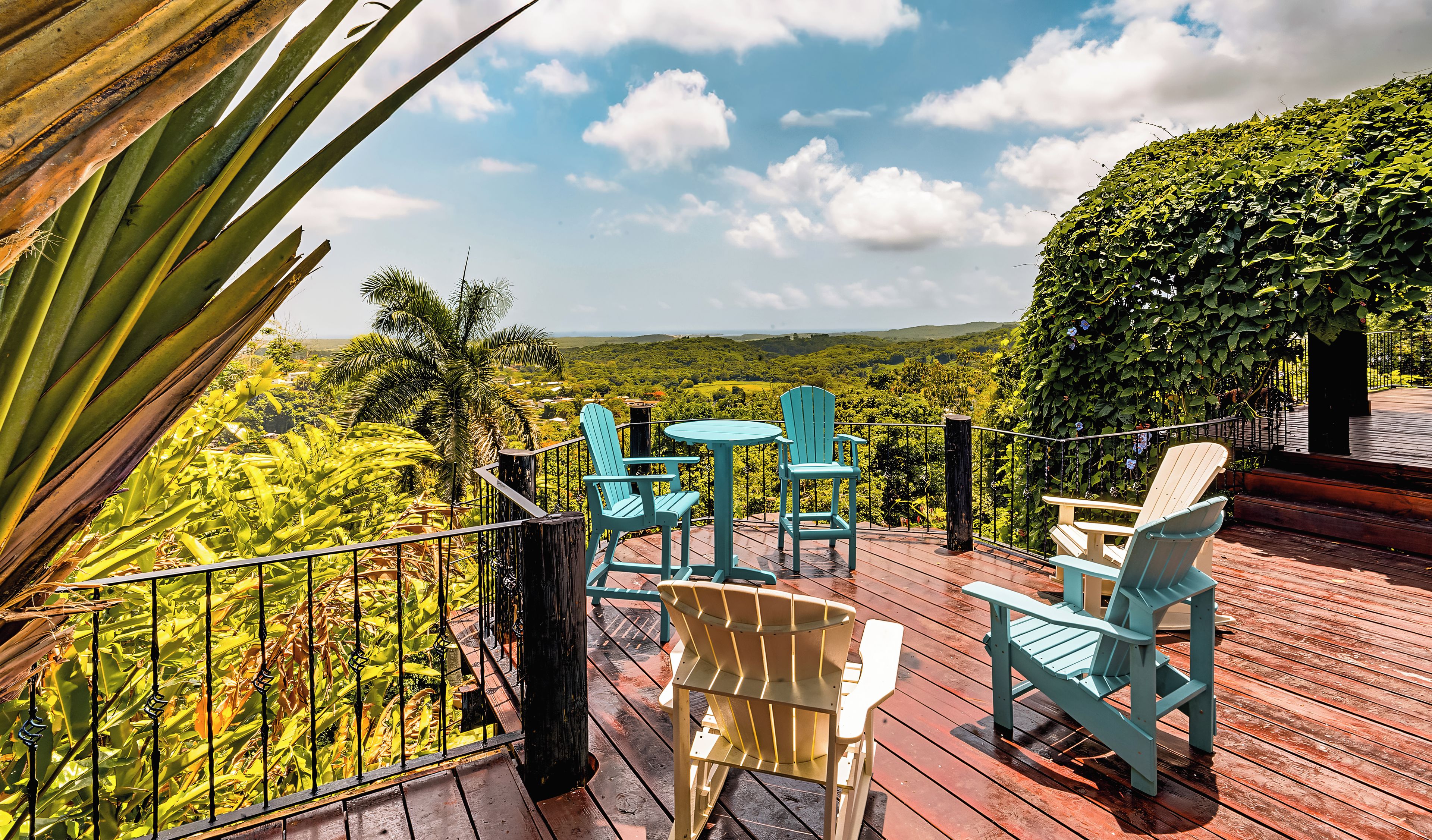 Terraza de madera con mobiliario exterior y vistas a un paisaje exuberante.