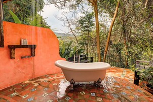 Un baño con bañera independiente, ducha y piso de cerámica.