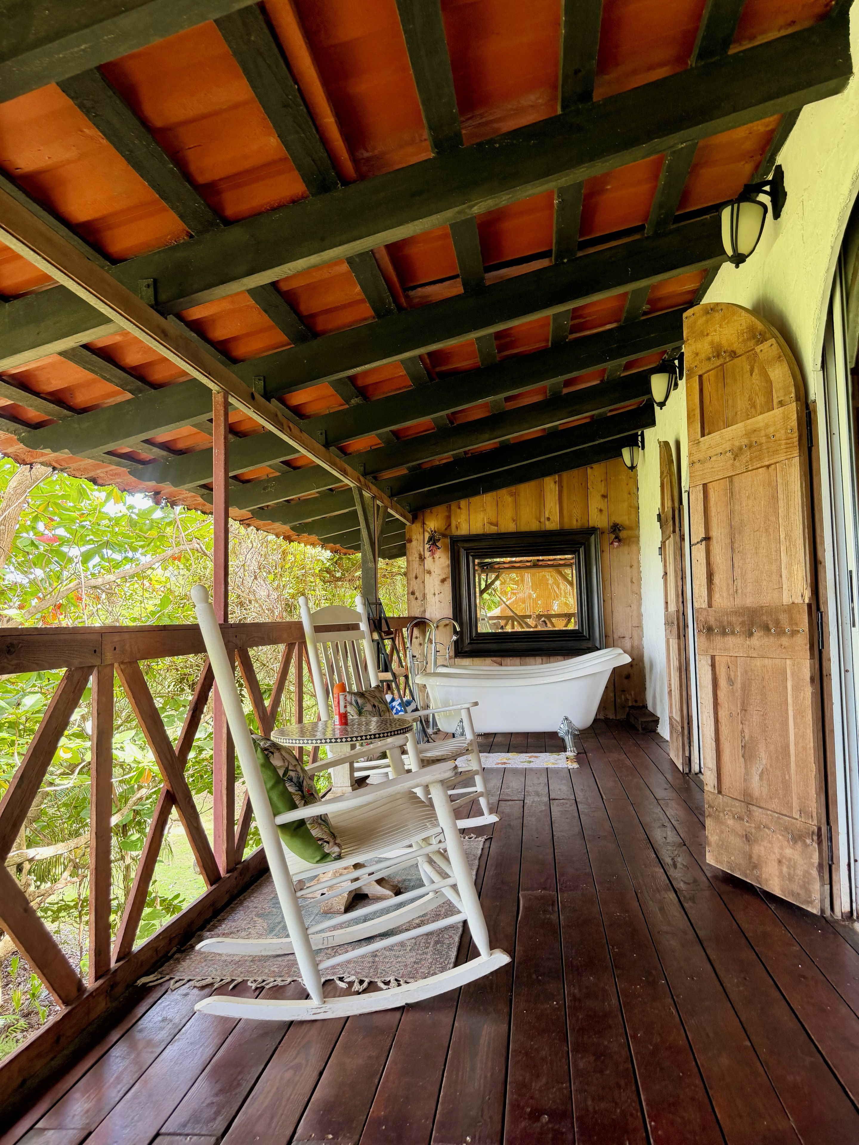 A wooden deck with a rocking chair, a table, and a bathtub.