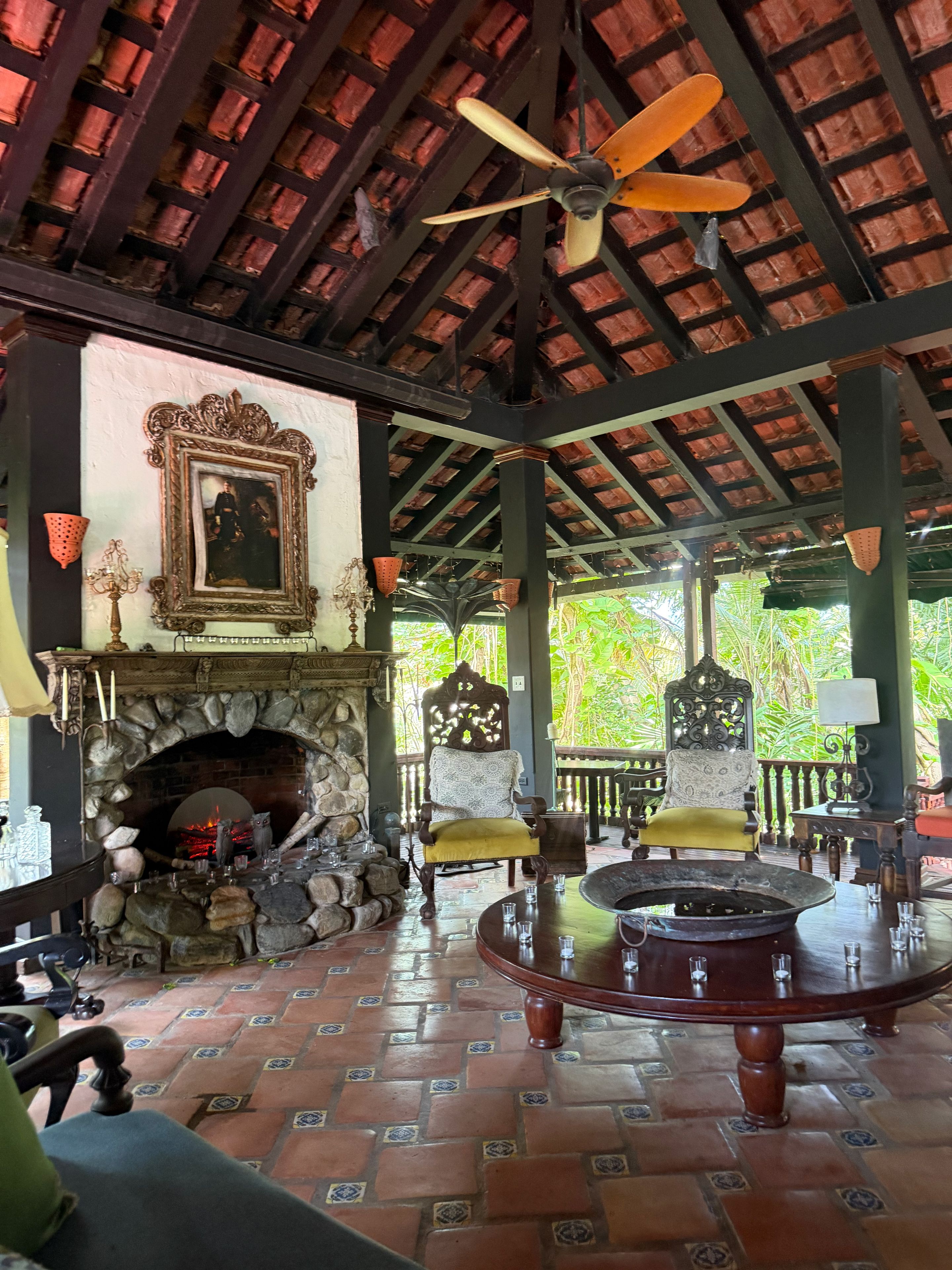Una habitación con chimenea de piedra, ventilador de techo y vistas al exterior.