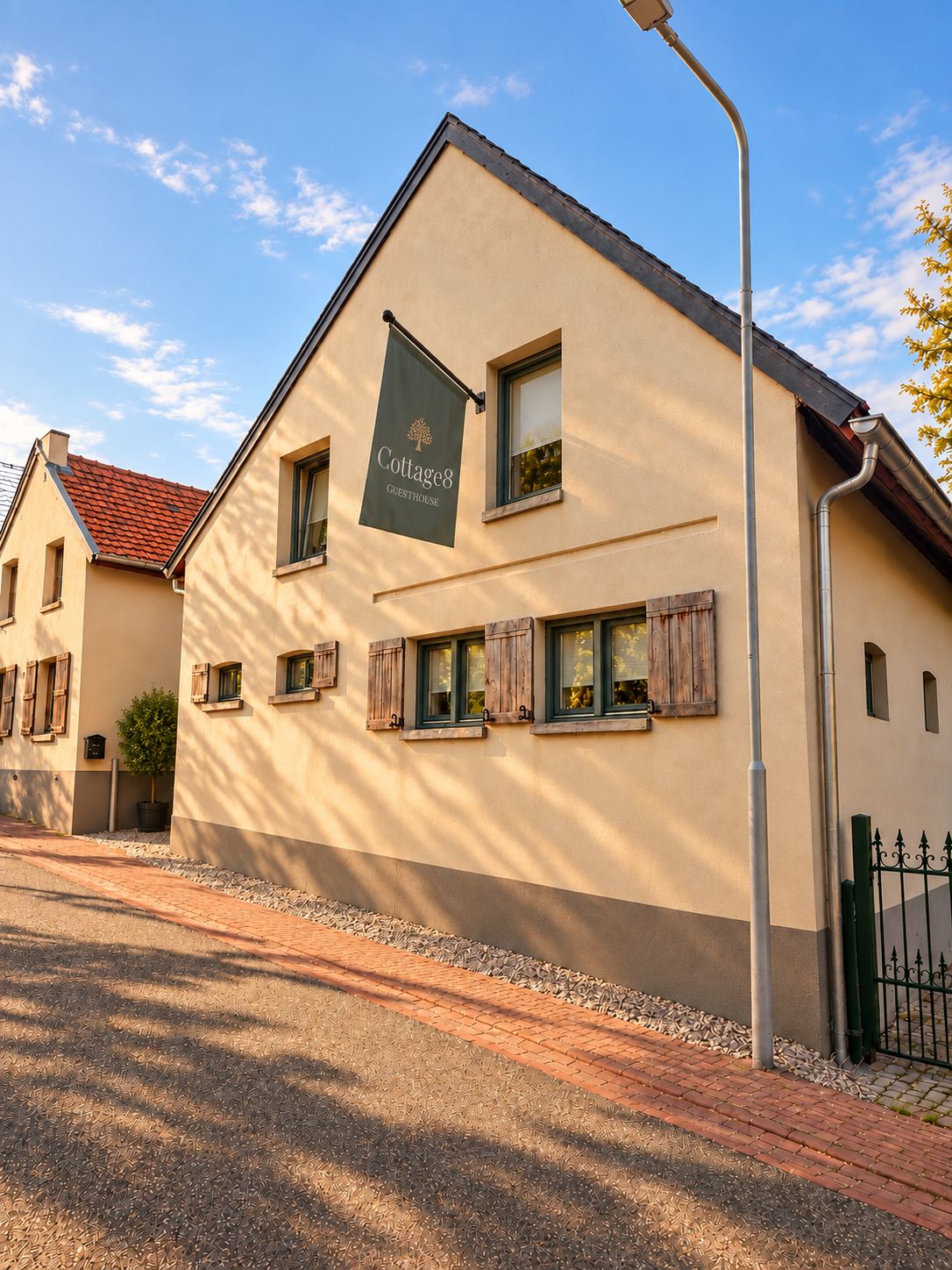 A building with a sign reading 'Cottage8 Guesthouse' and a paved walkway in front.
