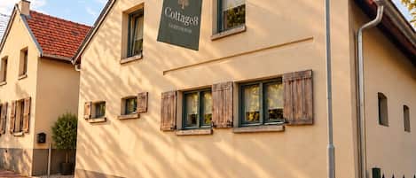 A building with a sign reading 'Cottage8 Guesthouse' and a paved walkway in front.