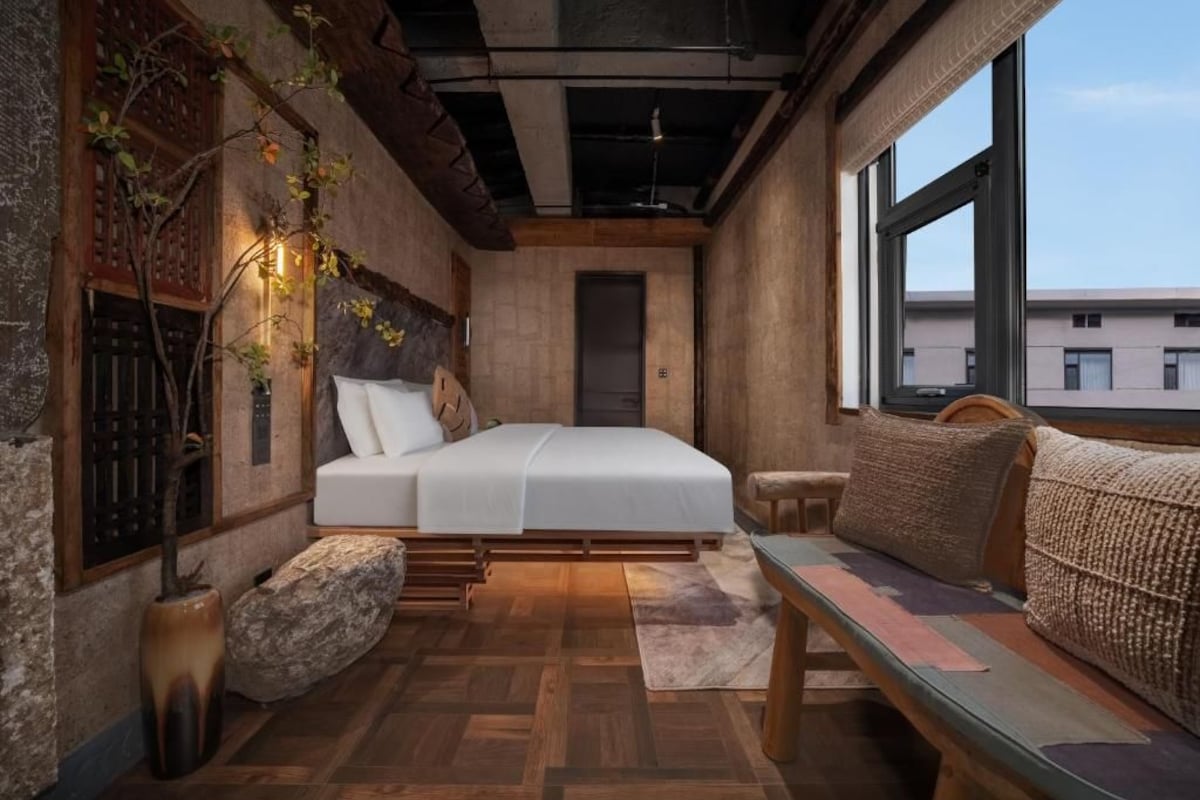 Un dormitorio con cama, un banco, una ventana y una puerta.