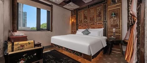 A hotel room with a large bed, a desk, a chair, a window, and a decorative ceiling.