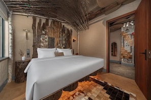 Un dormitorio con una cama grande, una pared rústica y un diseño único en el suelo de madera.