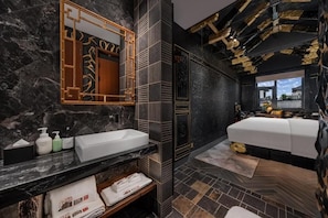 Un baño moderno con lavamanos de mármol, un espejo grande y una cama con vistas.