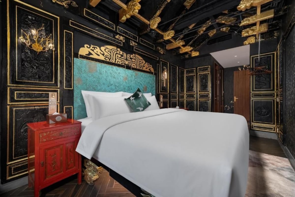 Una habitación con cama, un armario rojo y un techo decorativo.