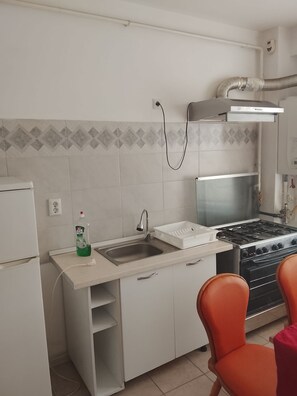 A kitchen with a sink, stove, and chairs.