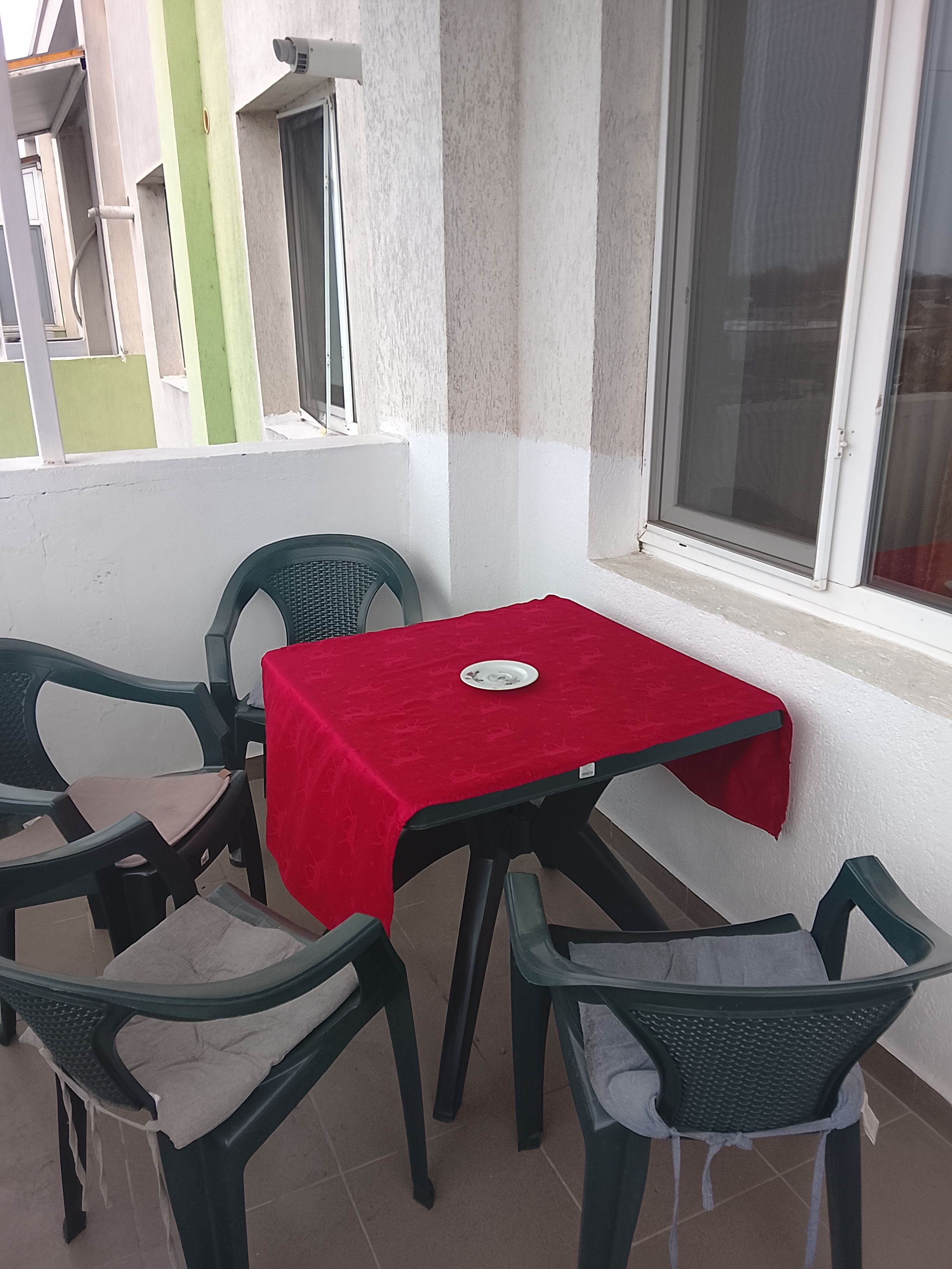Ein kleiner Außenbereich zum Essen mit einem roten Tisch und vier Stühlen.