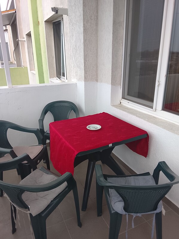 A small outdoor dining area with a red table and four chairs.