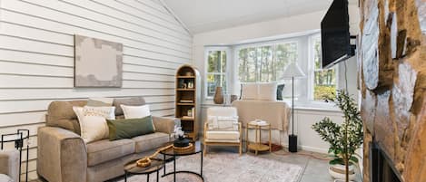 A cozy living room with a fireplace, a sofa, a coffee table, and a bookshelf.