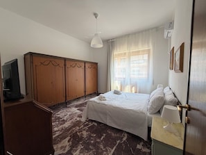 A hotel room with a bed, a wardrobe, a television, and a window with curtains. - New Listing (Roma)