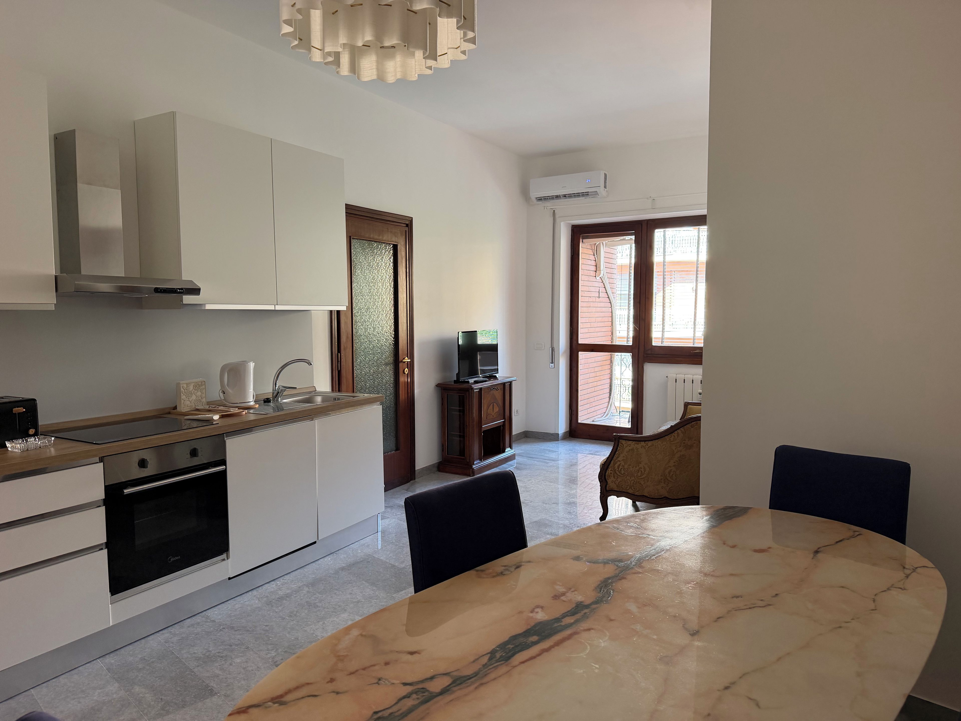 A modern kitchen with a dining area, a built-in oven, and a large window.