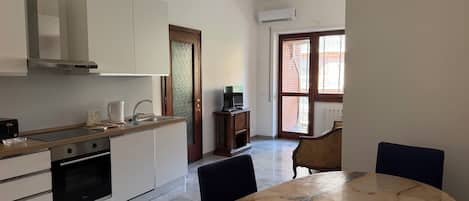 A modern kitchen with a dining area, a built-in oven, and a large window.