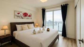 A bedroom with a large bed, a nightstand with a lamp, a painting on the wall, and a view of the city through the window.