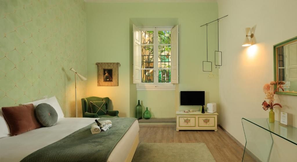 A bedroom with a bed, a chair, a TV, a dresser, and a window.